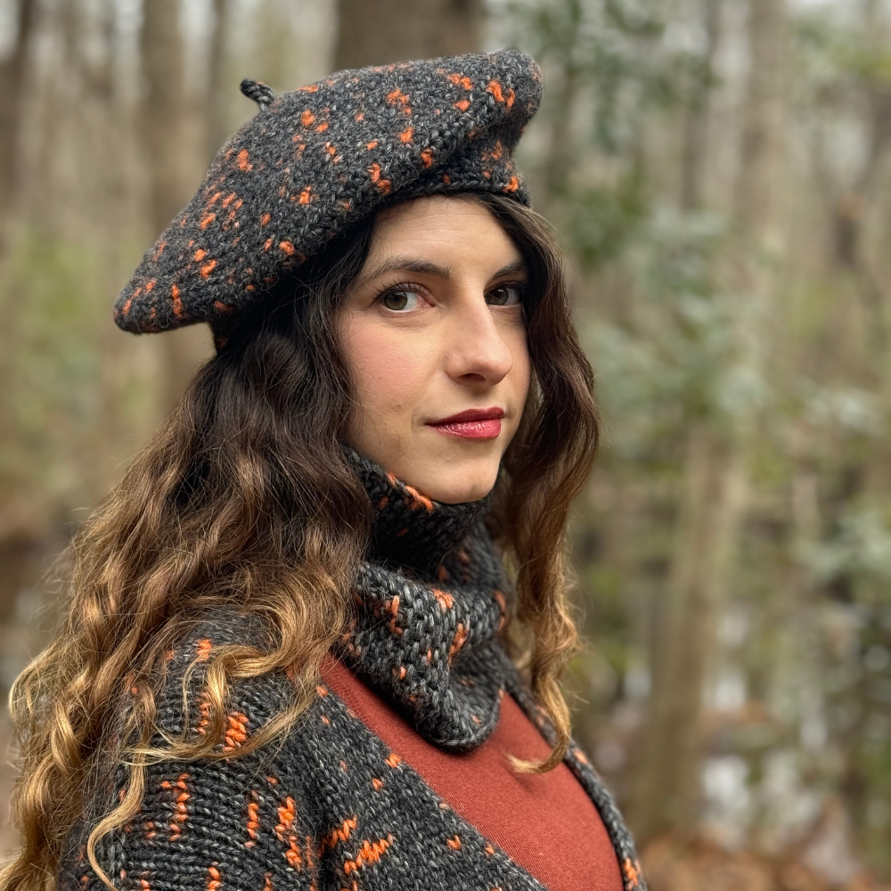 Woman wearing a patterned beret and scarf in a forest setting