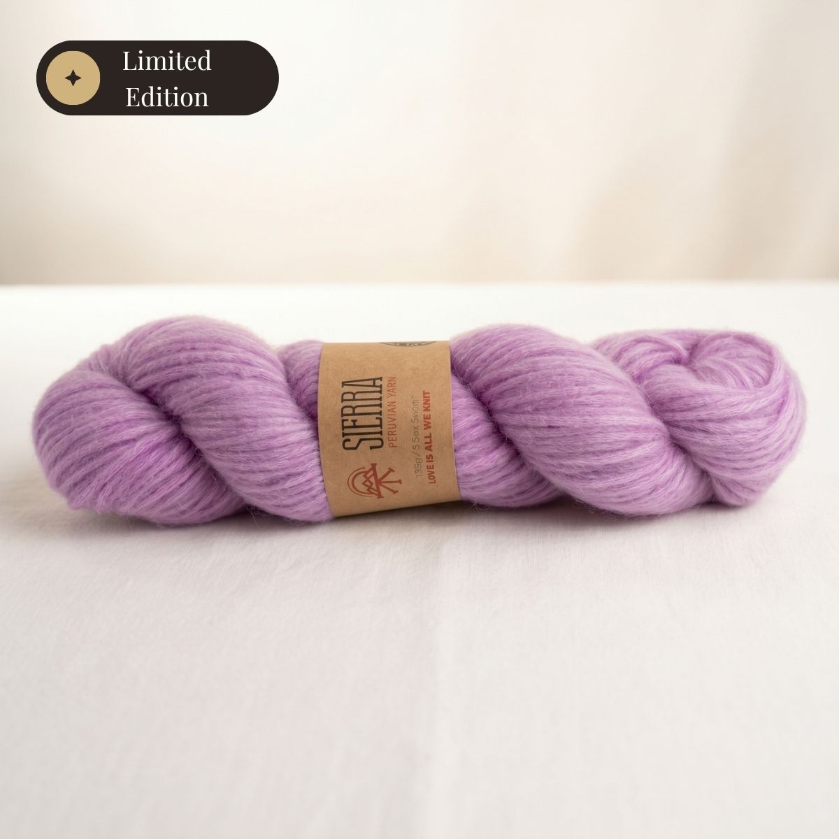 Andean Solid Lavender skein of Cloudtouch Baby Alpaca Pima Cotton Blend for knitting kits by Sierra Yarns, with a kraft paper label reading “Love is all we knit.”