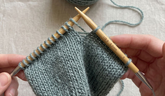 Knitter working stockinette flat on bamboo circular knitting needles showing the flexible cable joining the two needle tips