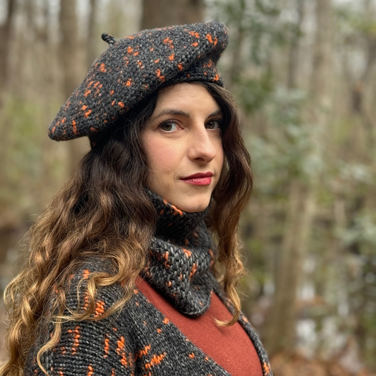 Woman wearing a patterned beret and scarf in a forest setting