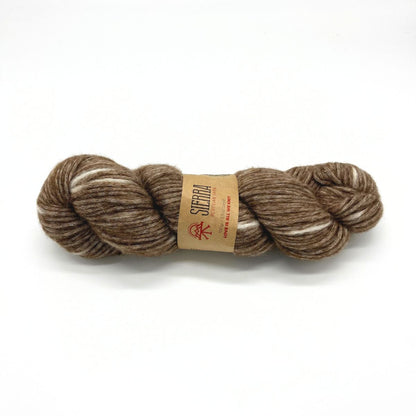 Brown skein of yarn with a label on a white background