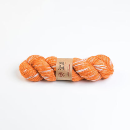 Orange and white yarn skein with a label on a white background